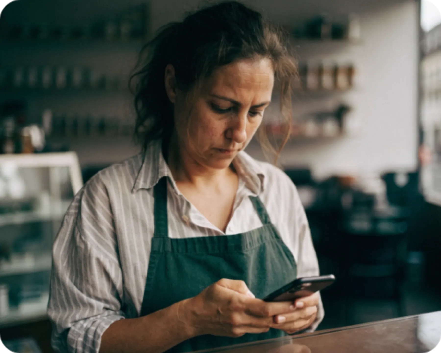 A shop owner checking her reviews on a phone behind the counter