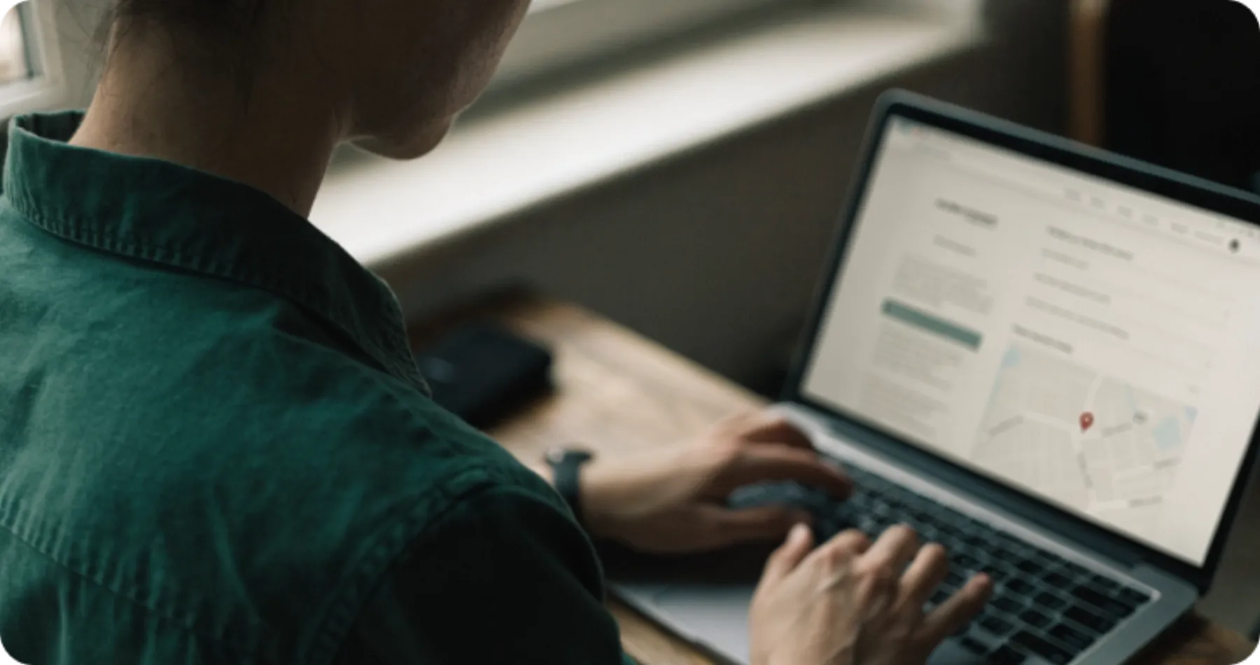 Someone working at a laptop by a window, a dashboard open on the screen